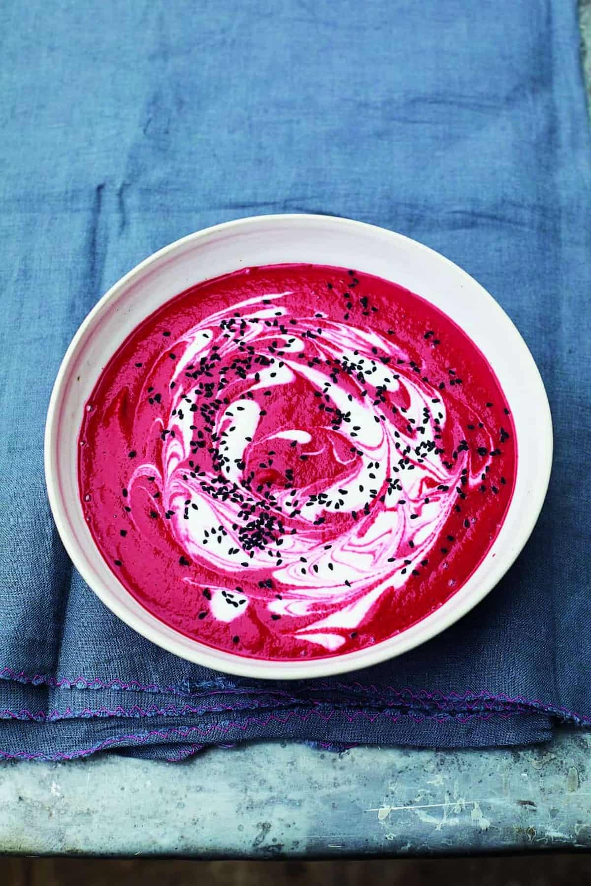 Vibrant beet and ginger soup topped with vegan yogurt and nigella seeds.