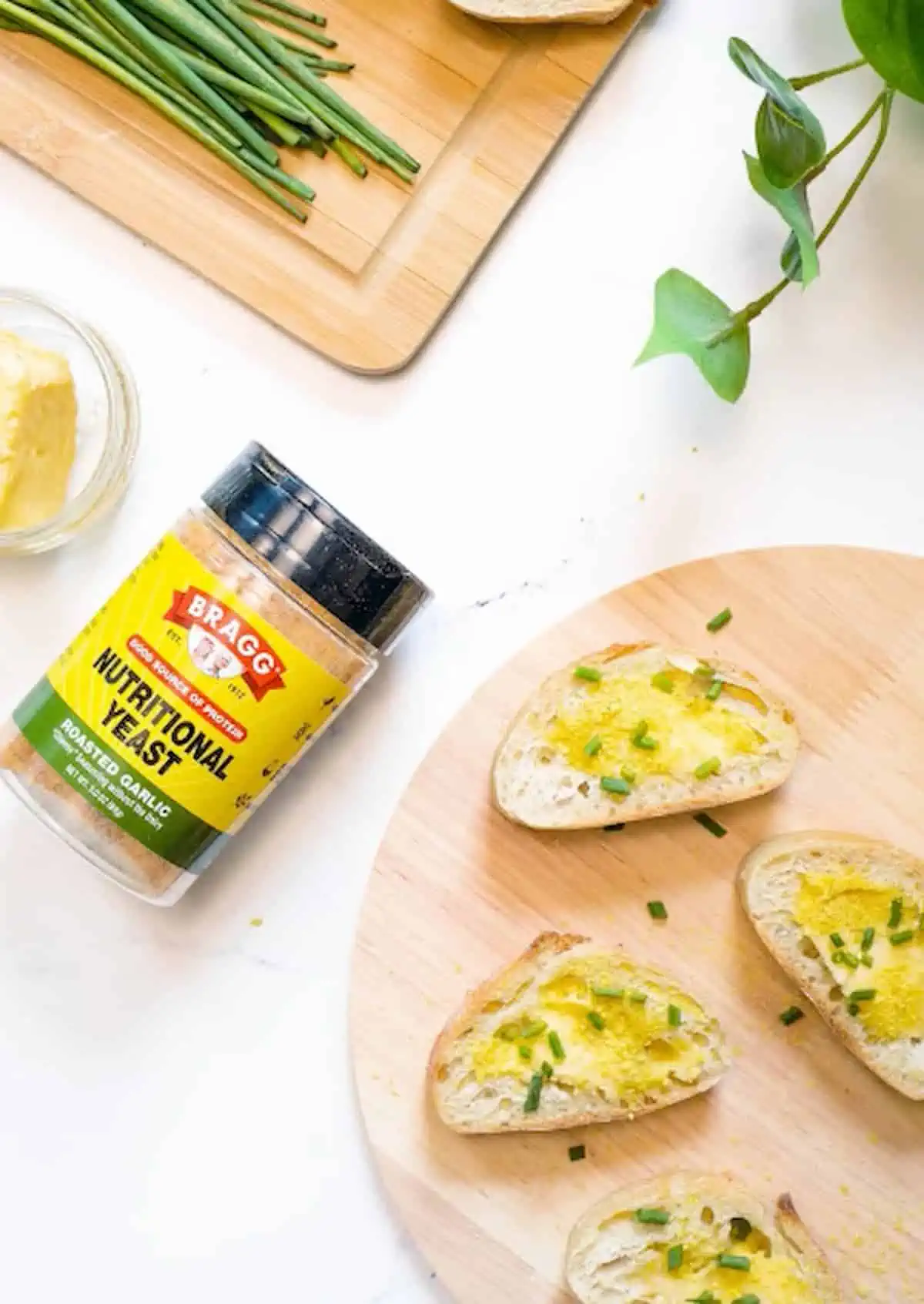 Bragg Nutritional Yeast container next to roasted garlic nooch or toasted baguette.