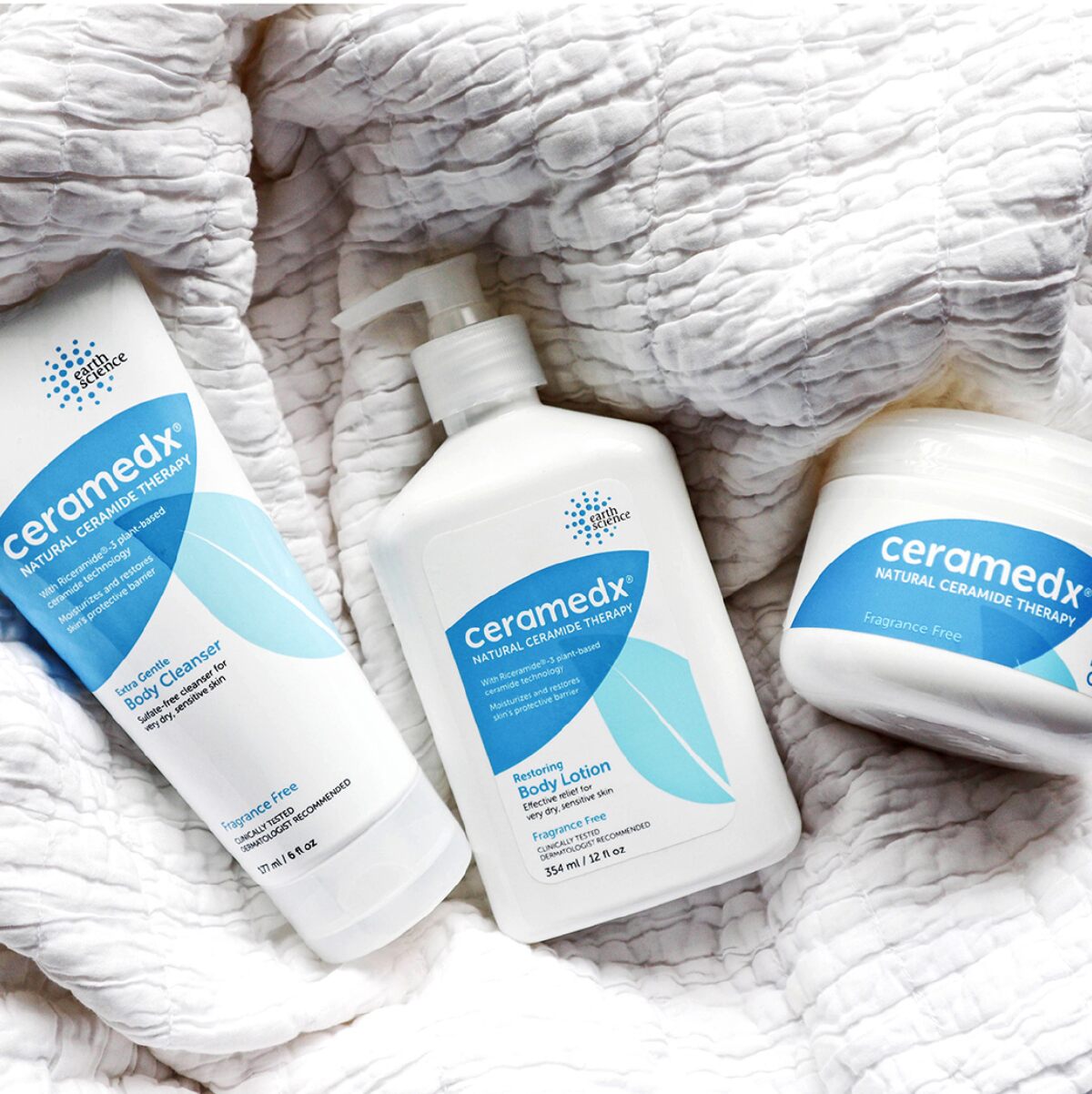 A white and blue tube, pump bottle and jar of Ceramedx skin cream against a light gray blanket background.