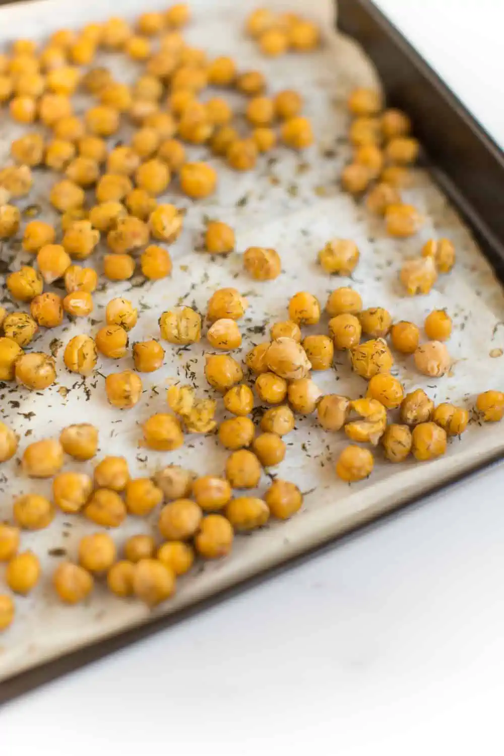 Roasted chickpeas with dried dill on a baking tray.