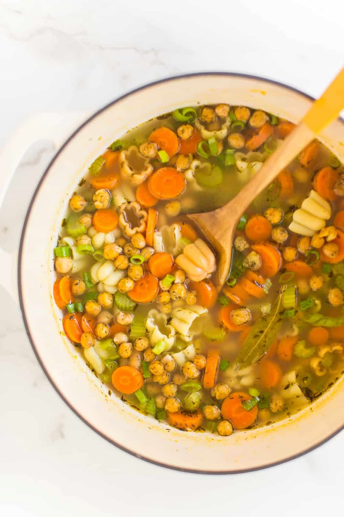 Colorful pot of chickpea noodle soup with carrots, noodles, and chickpeas.