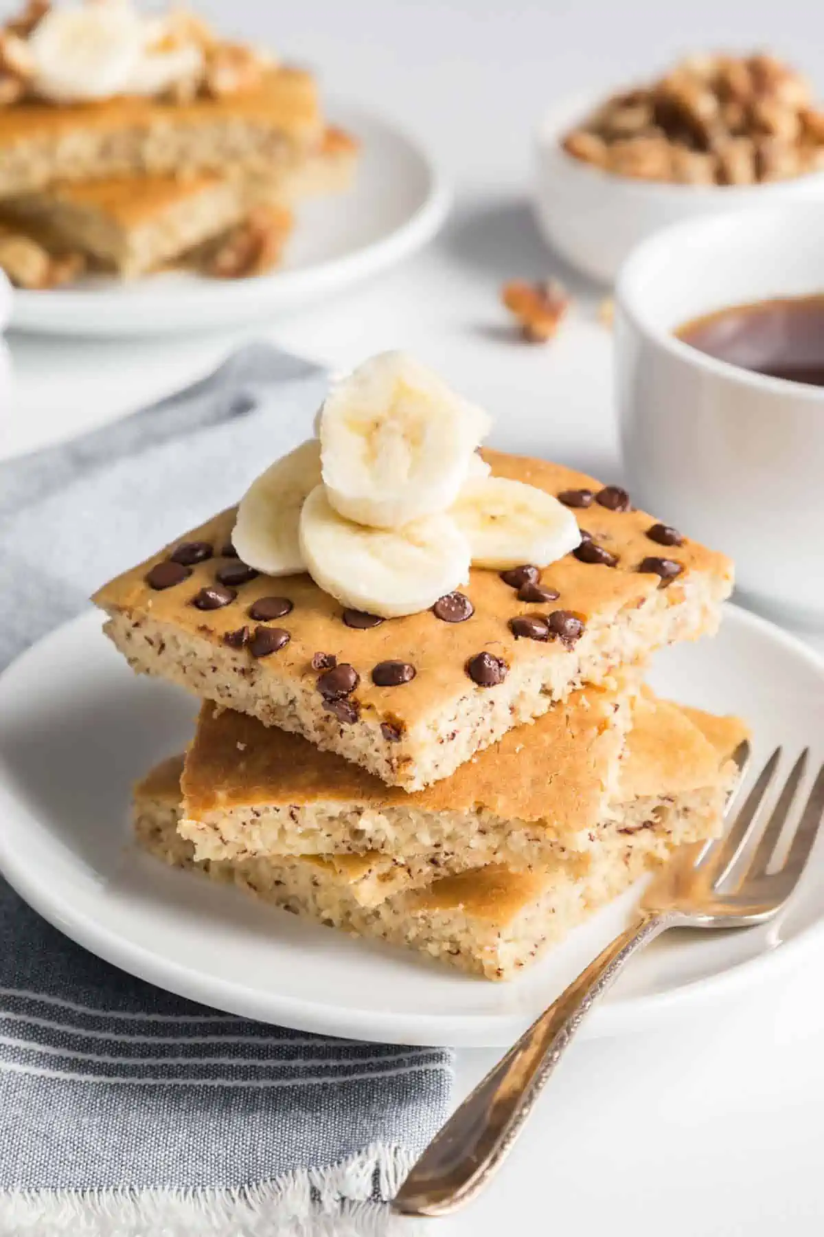 Vegan sheet pan pancakes stacked on a plate, topped with banana slices.