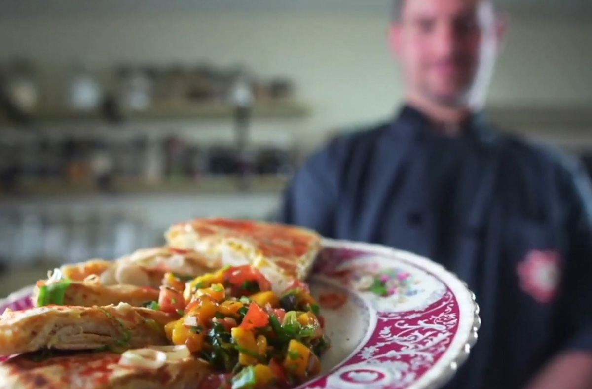 Chef Adam Sobel holding up a plate of vegan food.