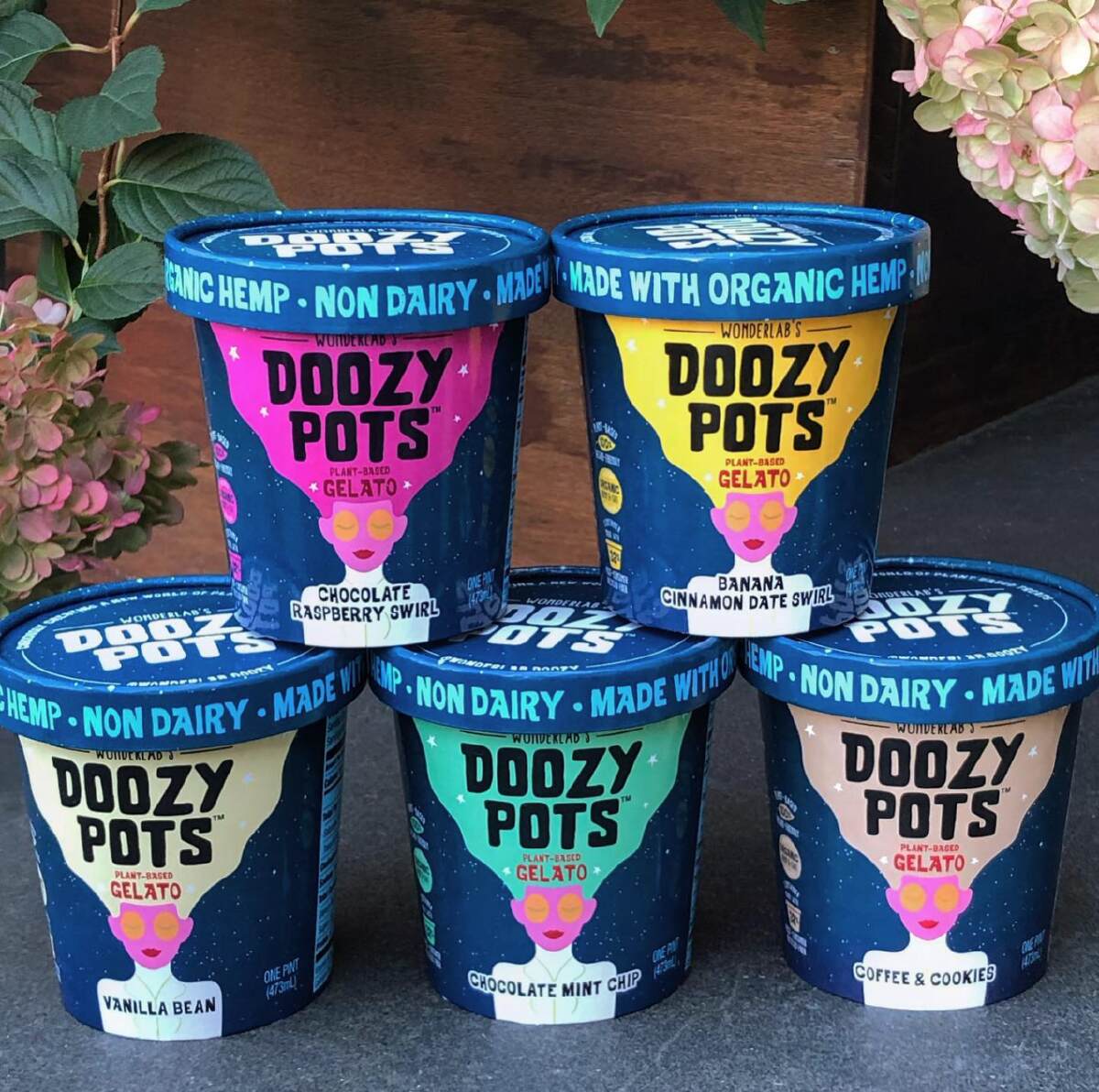 Five pints of Wonderlabs Doozy Pots non dairy gelato on a slate table against a wooden background with hydrangeas.