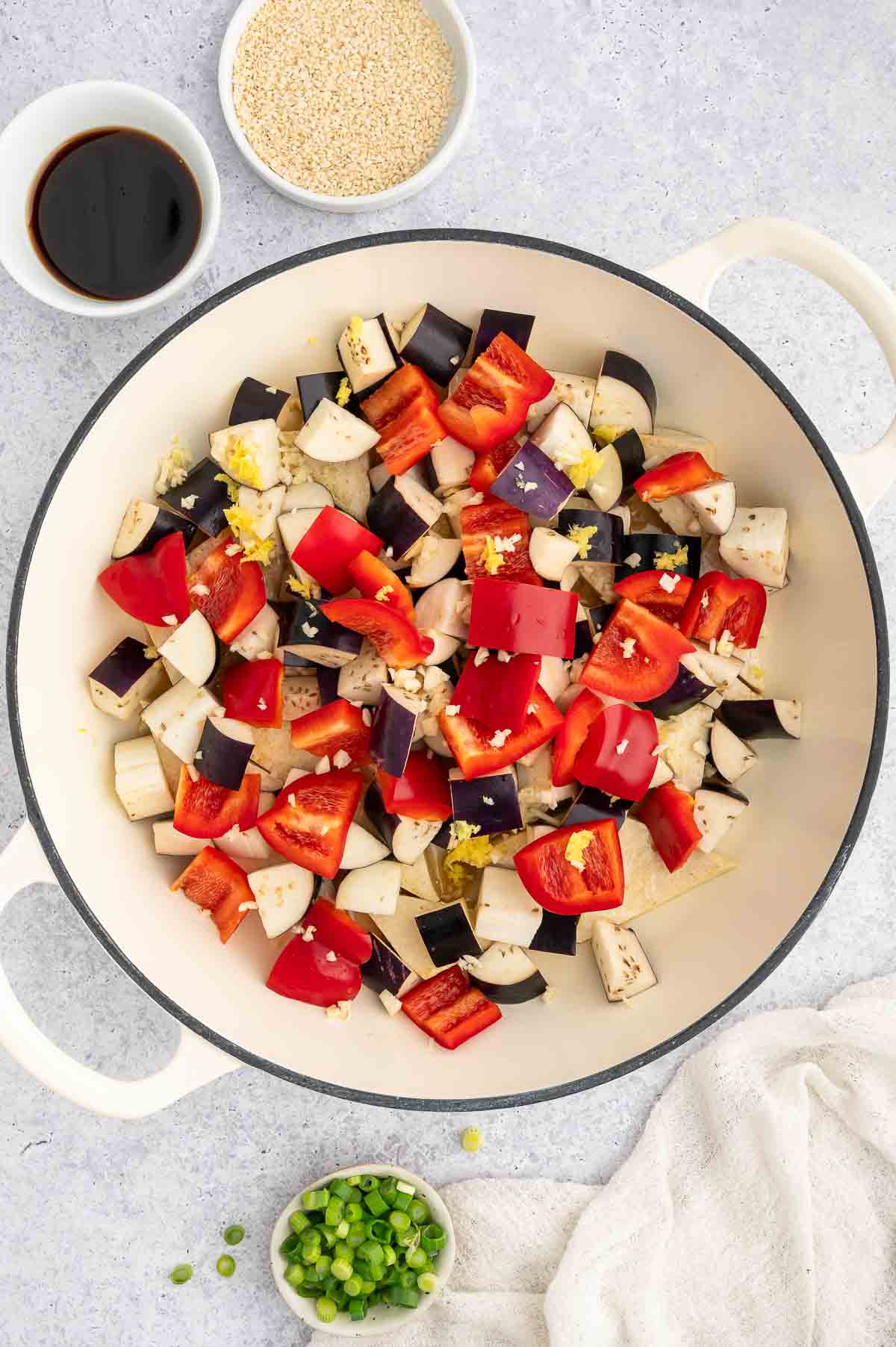 Eggplant and red bell peppers in a pan.
