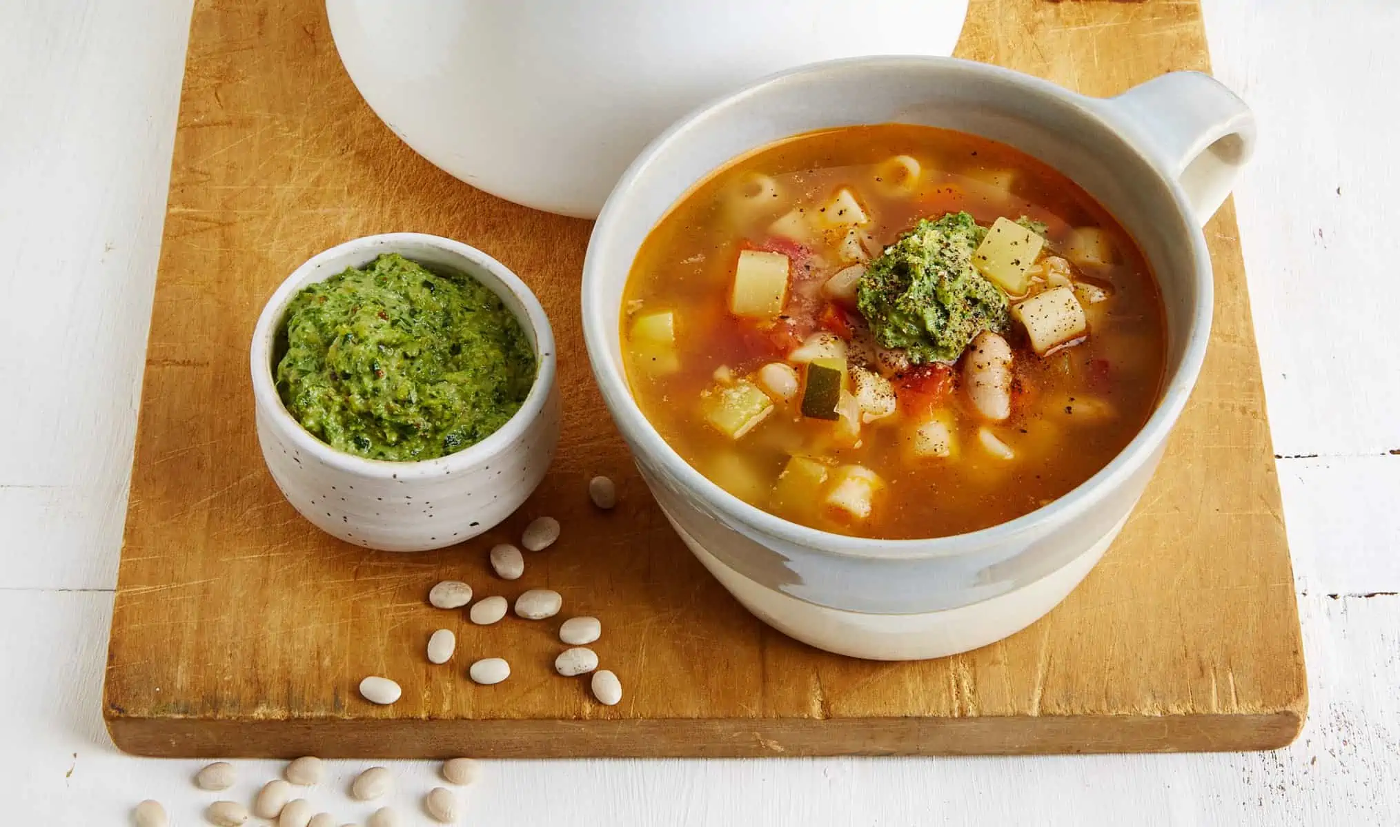 French pistou soup served in a bowl next to a small container of pistou.