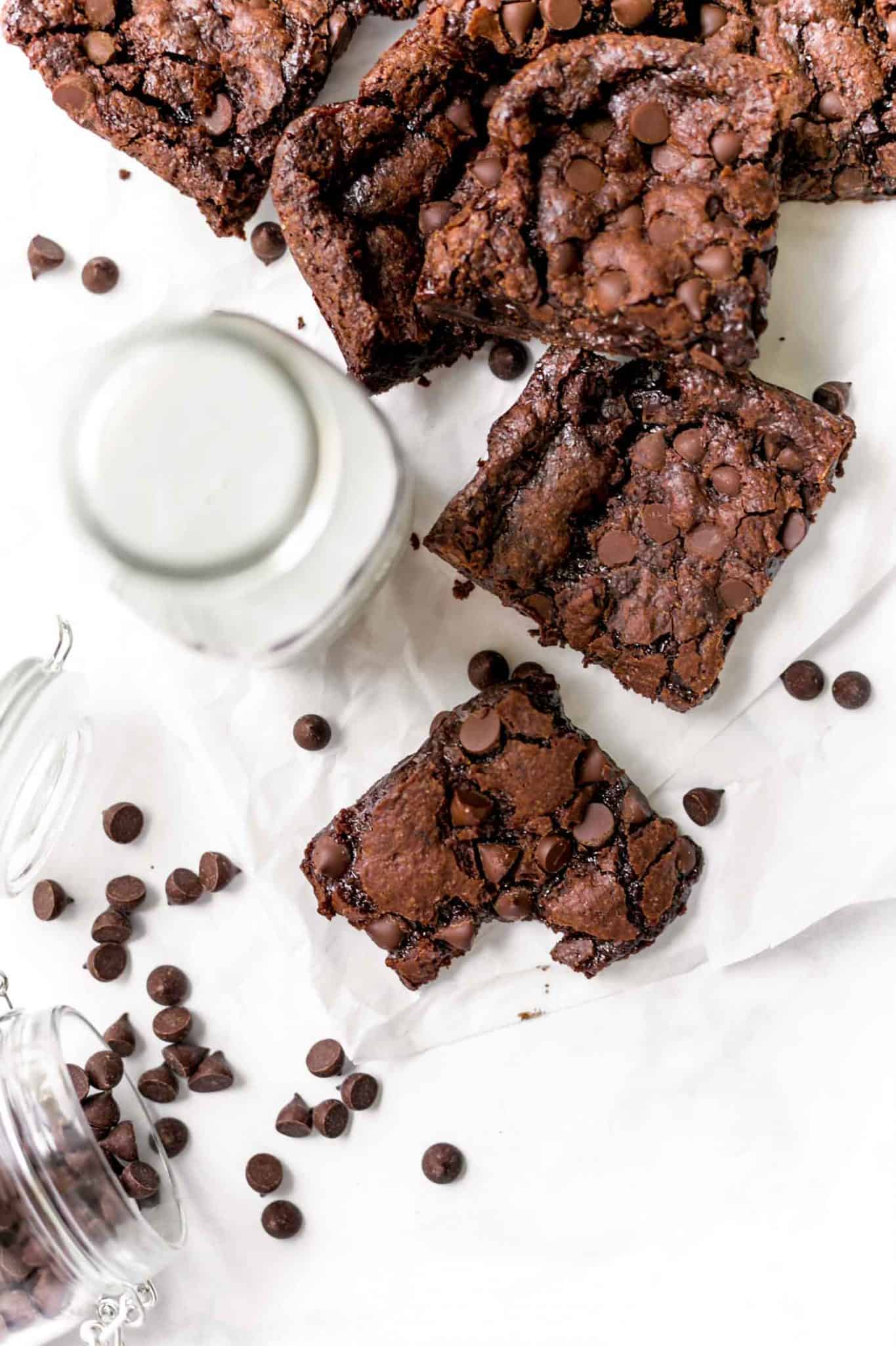 Dairy-free brownies scattered on a tabletop with a jar of plant-based milk.
