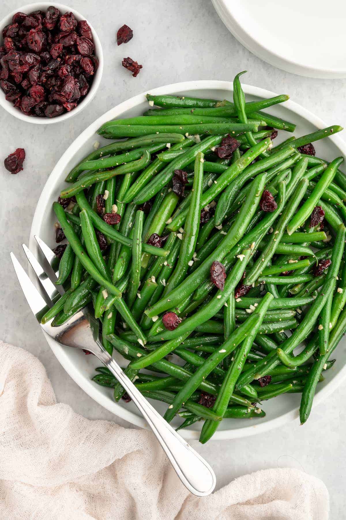 Garlic green beans with cranberries on a white plate.