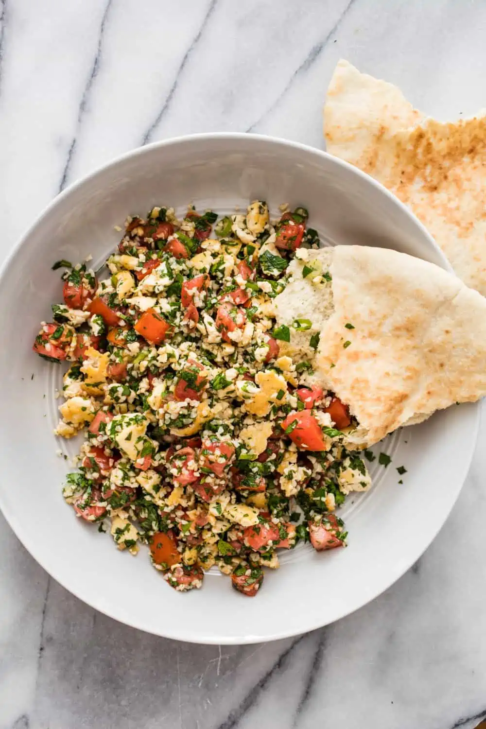 Tofu tabbouleh salad in a bowl served with a side of pita bread.