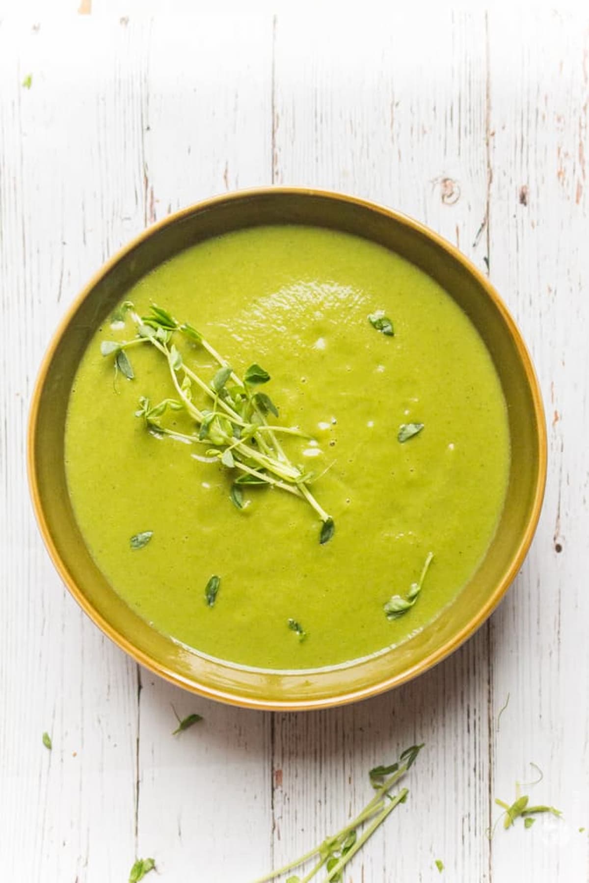 Bright green vegan detox soup made with broccoli, peas, and herbs.