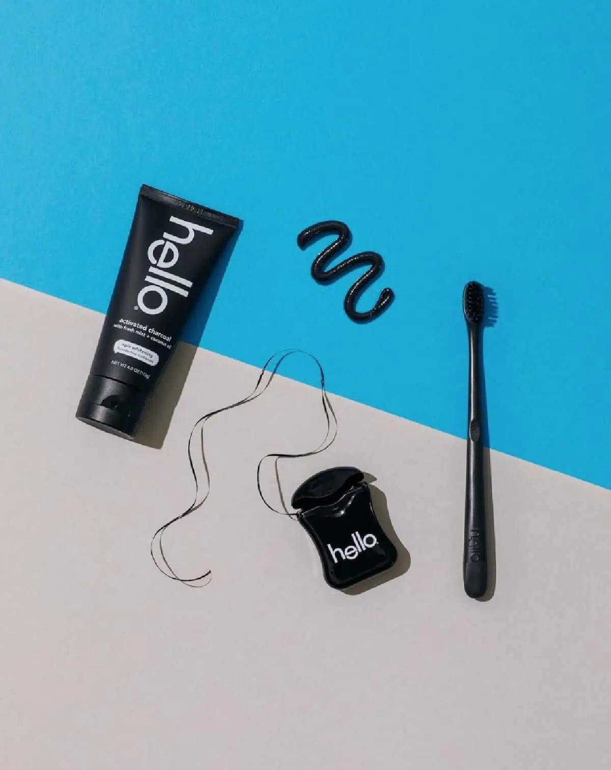 Hello toothpaste, toothbrush and floss container in black against a white and blue background.