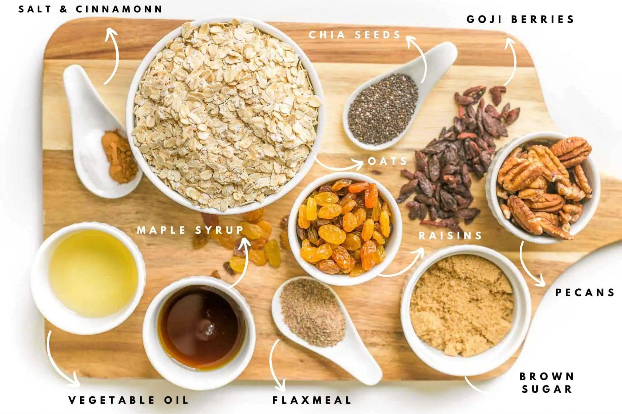 Wooden board with small bowls and ceramic spoons with each ingredient for the maple brown sugar granola