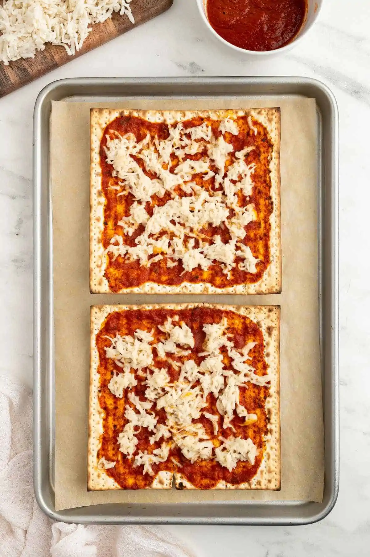 Two cheese matzah pizza that have been baked on a baking tray.