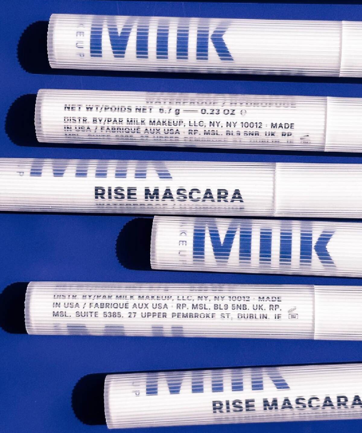 White Milk Makeup mascara tubes with blue writing against a blue background.