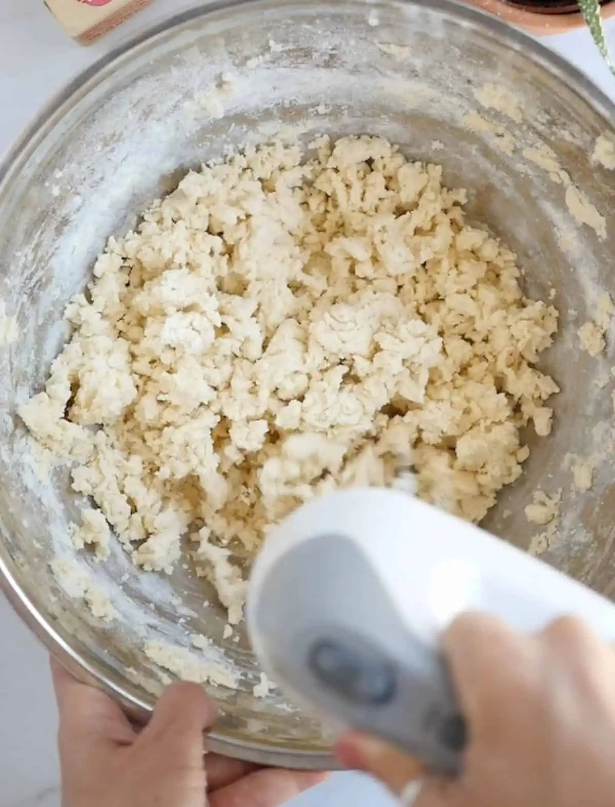 A hand mixer whipping together the coconut oil, cane sugar, milk, and vanilla extract in a bow.