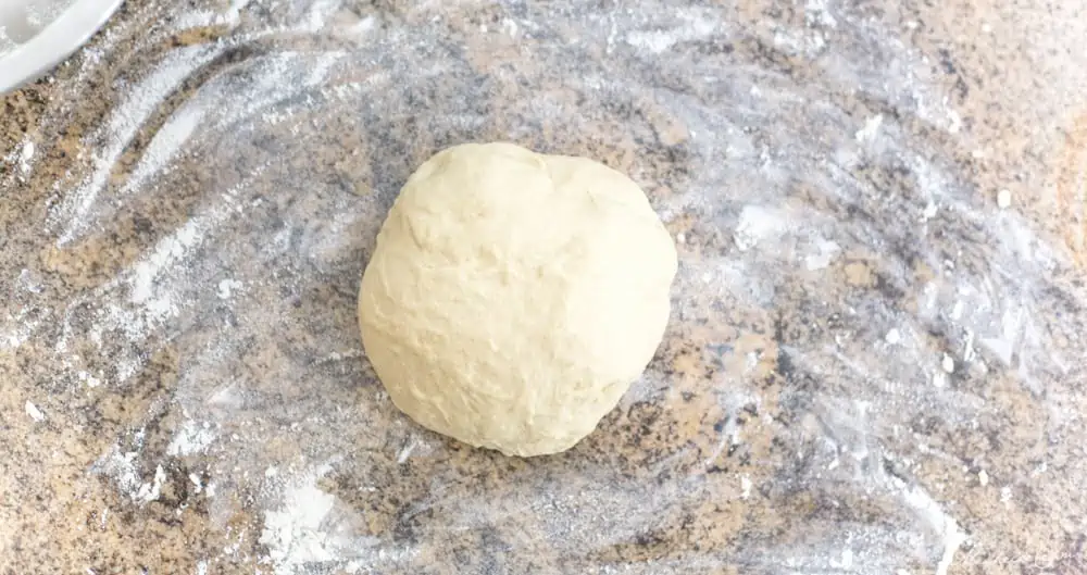 Ball of vegan focaccia dough on a floured surface.