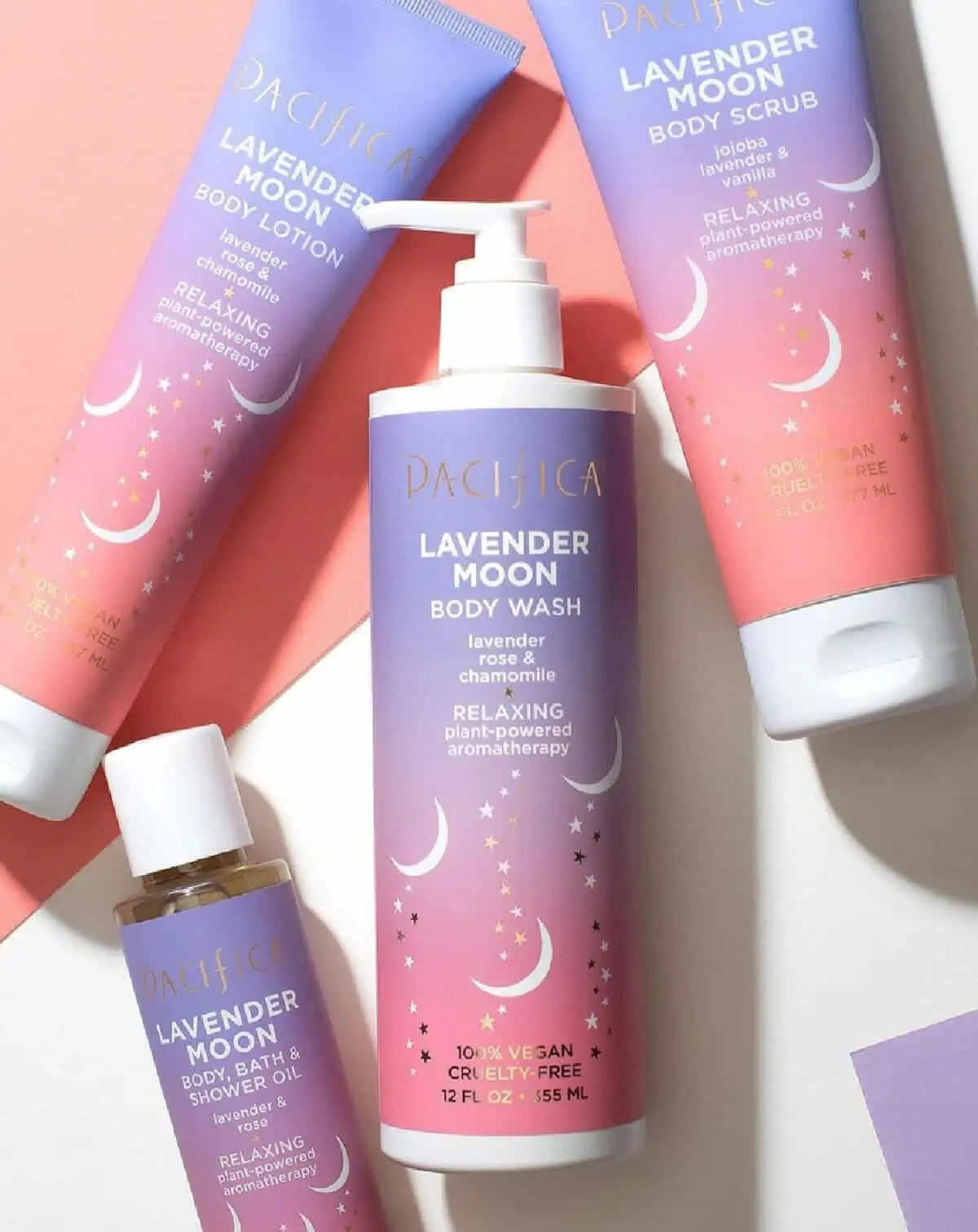 Four bottles of pink and purple Pacifica Beauty products (including vegan body wash) against a white and pink background.