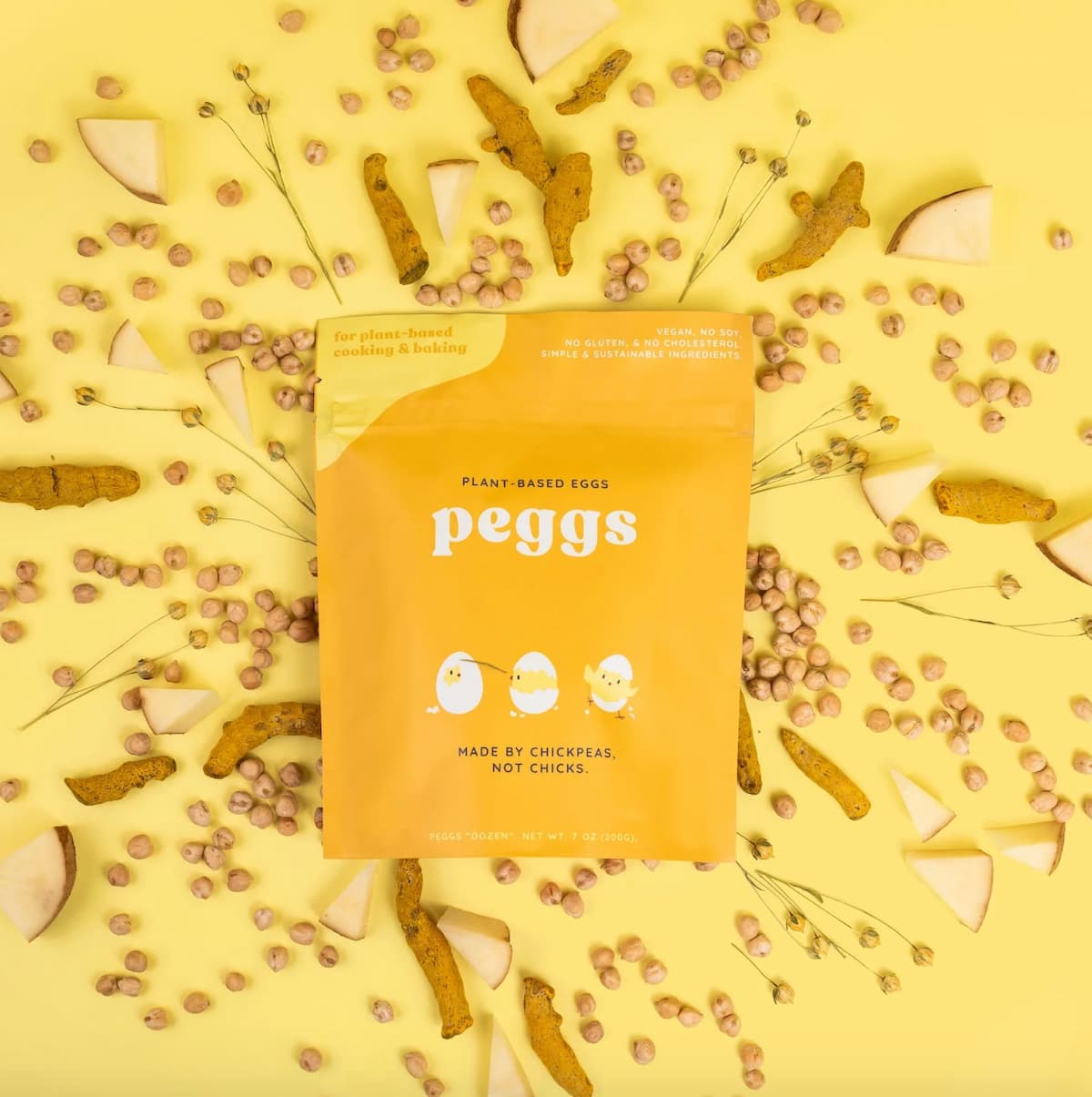 A yellow package of Peggs plant-based powered egg mix against a yellow background filled with chickpeas and flaxseed.