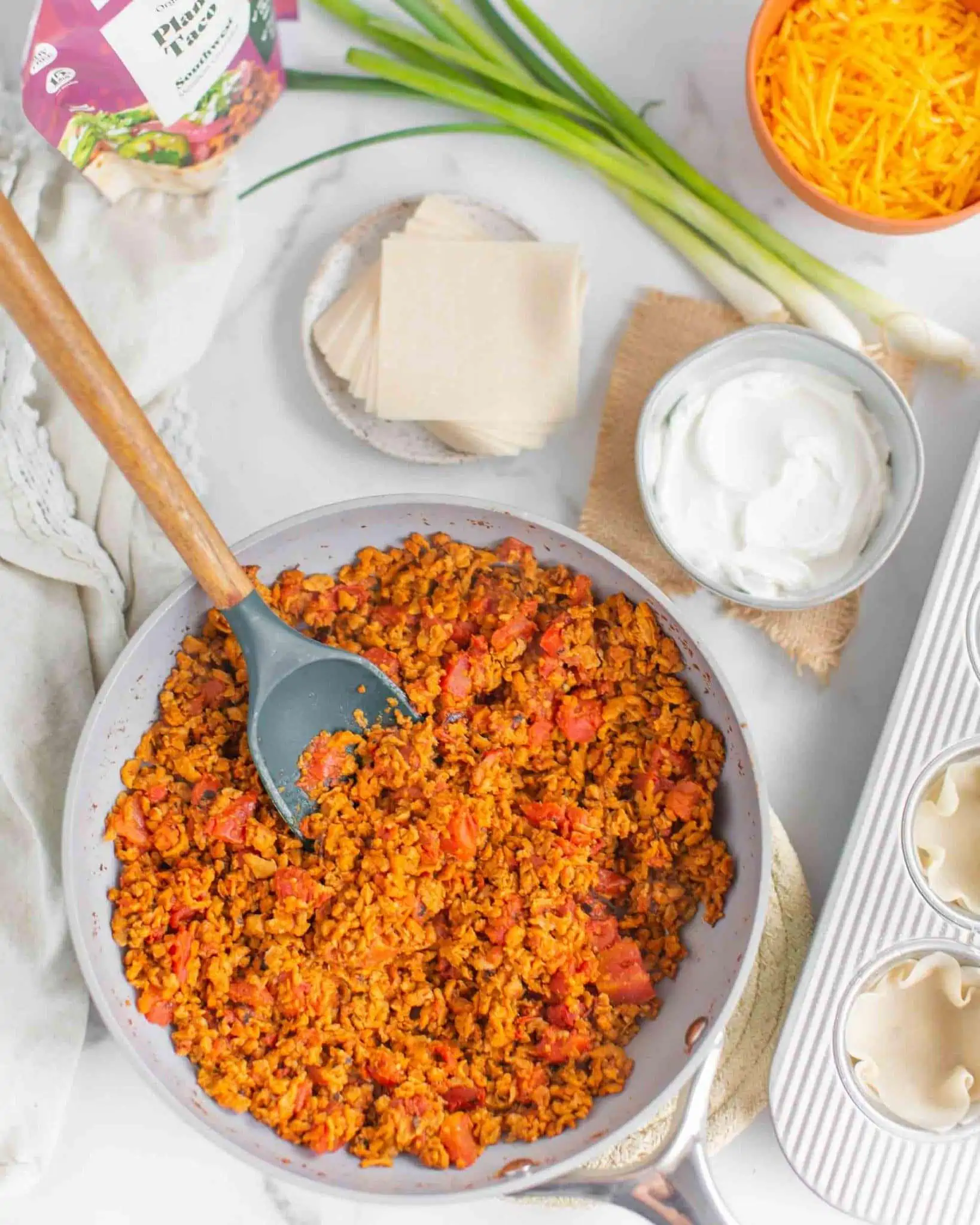 Vegan meatless crumbles in a skillet with a silicone spoon.