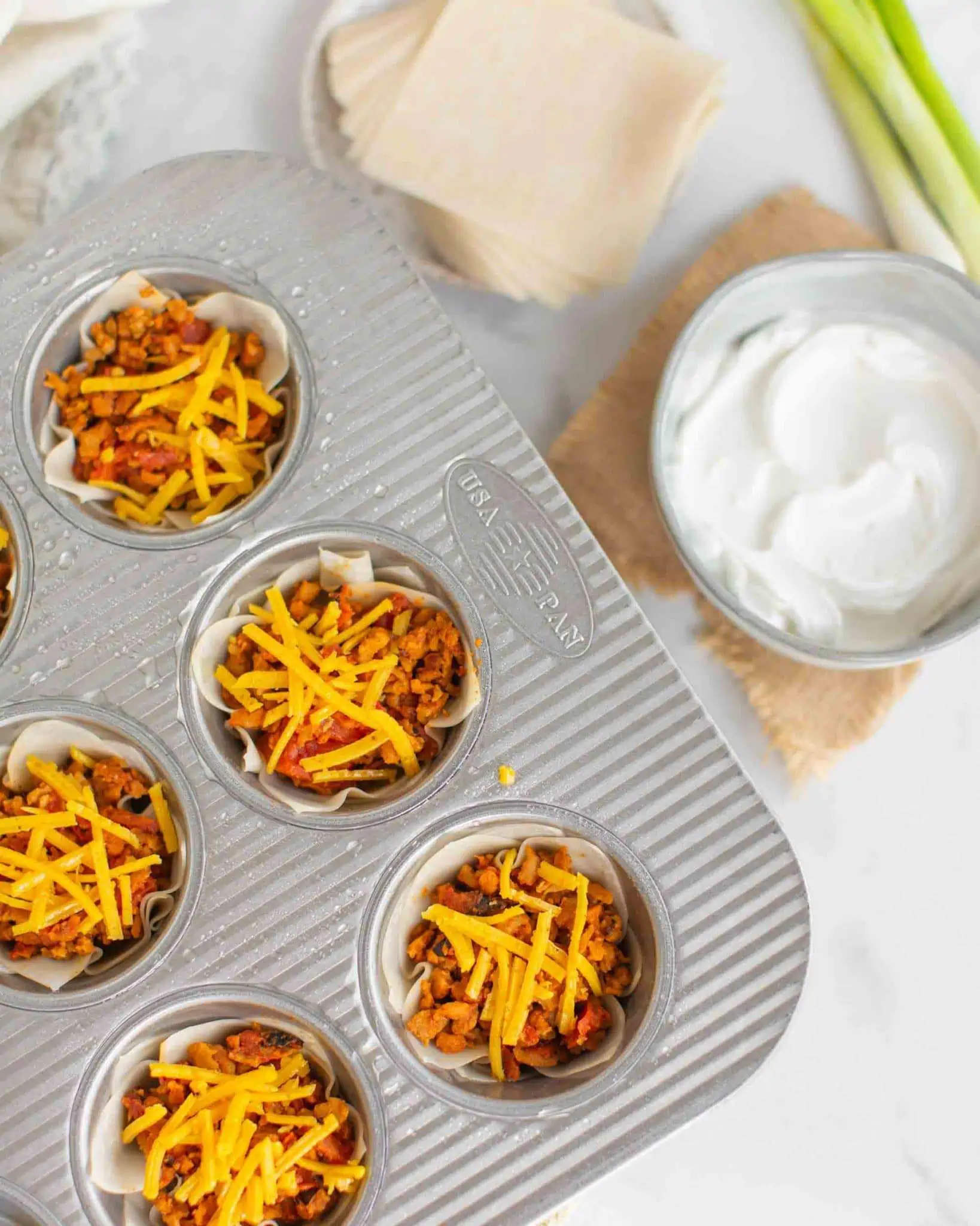 A muffin pan filled with vegan taco cups assembled and ready to be baked.