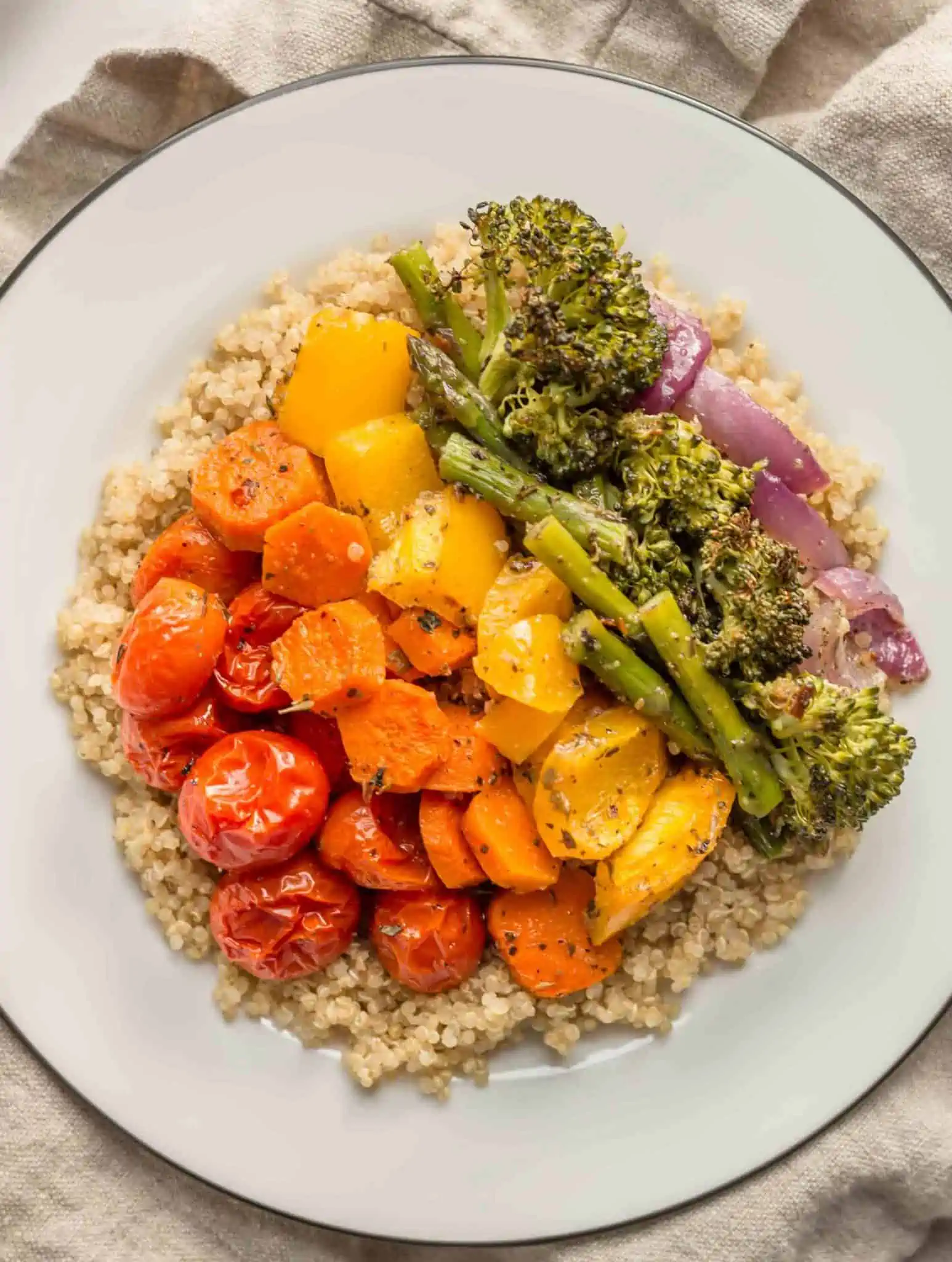 Dinner plate with healthy whole foods roasted rainbow veggies over quinoa.