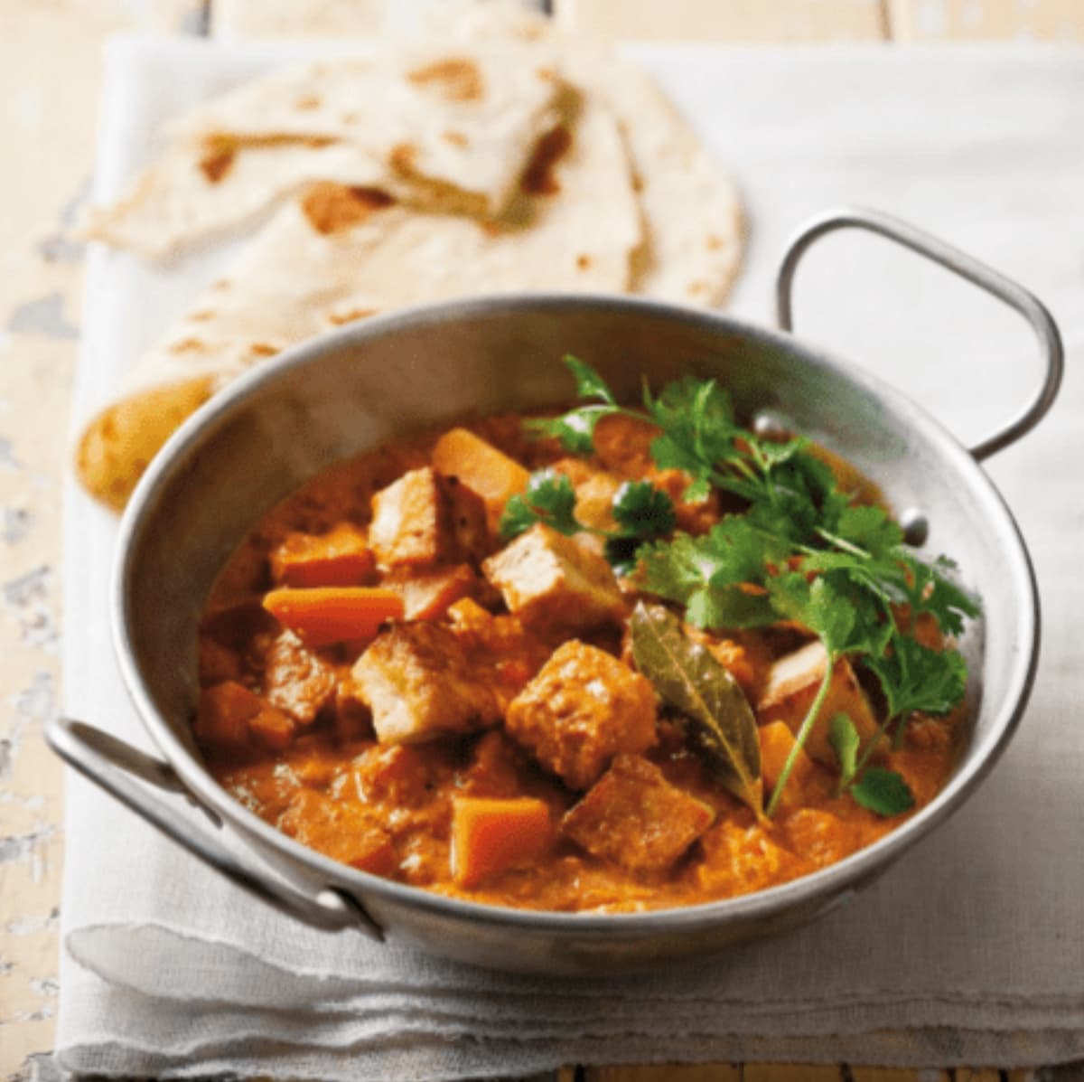 A bowl of slower cooker vegan red curry with tofu and garnished with parsley.