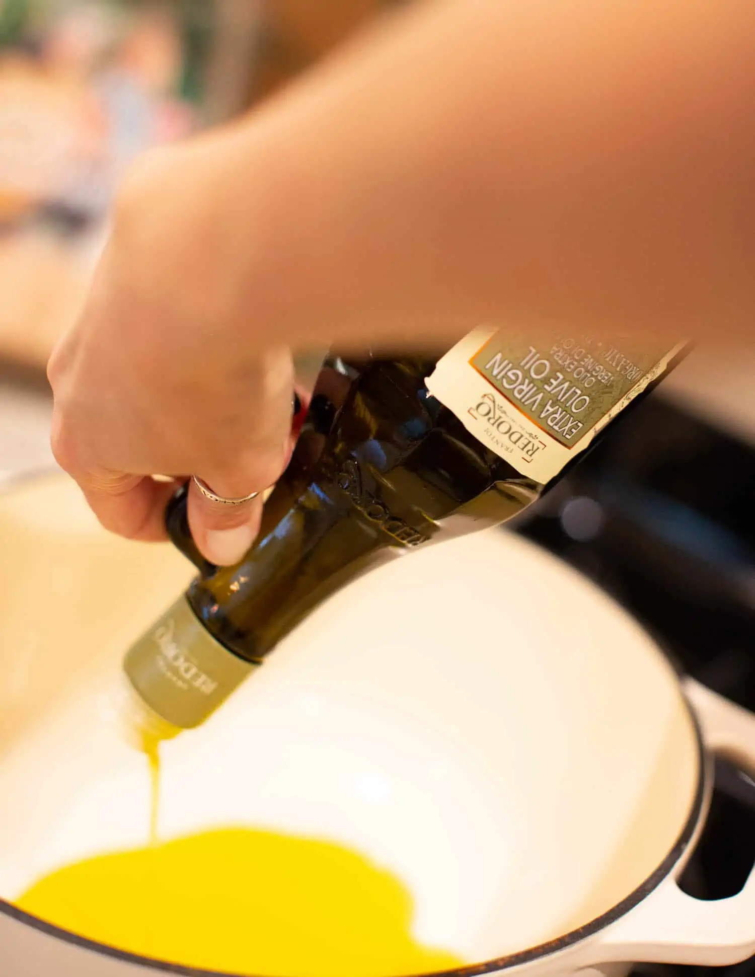 Pouring the olive oil into dutch oven pan for a spaghetti arrabiata recipe.