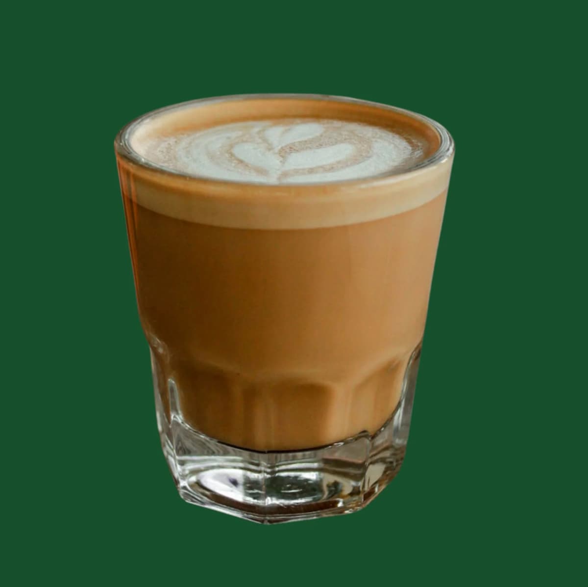 A clear glass filled with vegan Starbucks Brown Sugar Oatmilk Cortado on a dark green background.