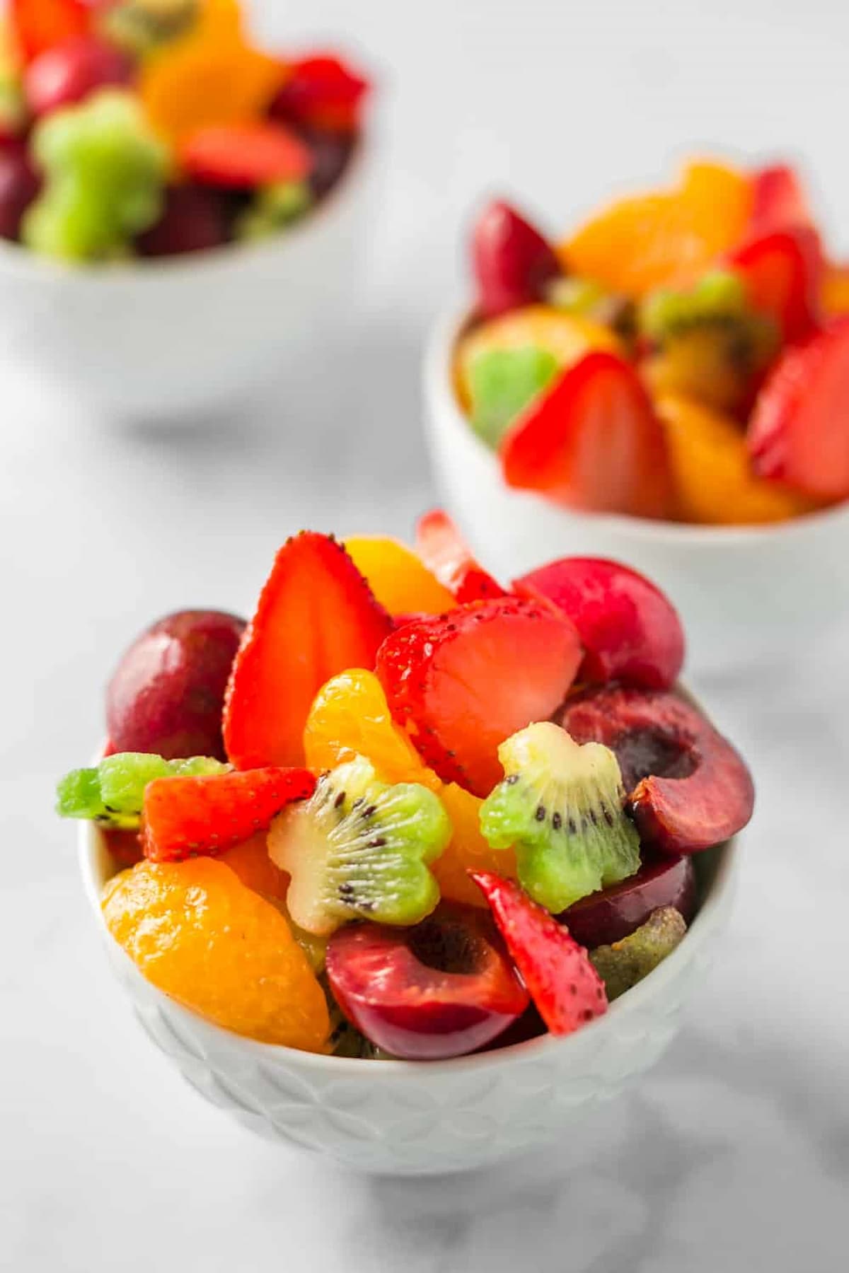 Colorful summer fruit salad with strawberries, kiwi, citrus, and cherries tossed in lime dressing.