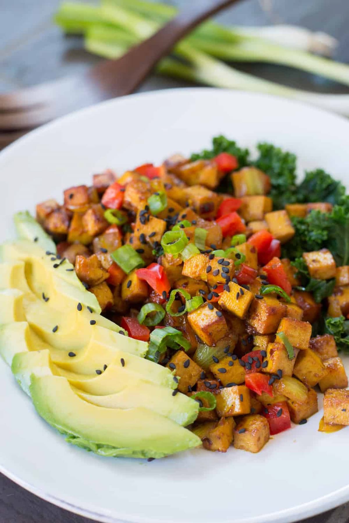 A plate of teriyaki tofu with sliced avocado.
