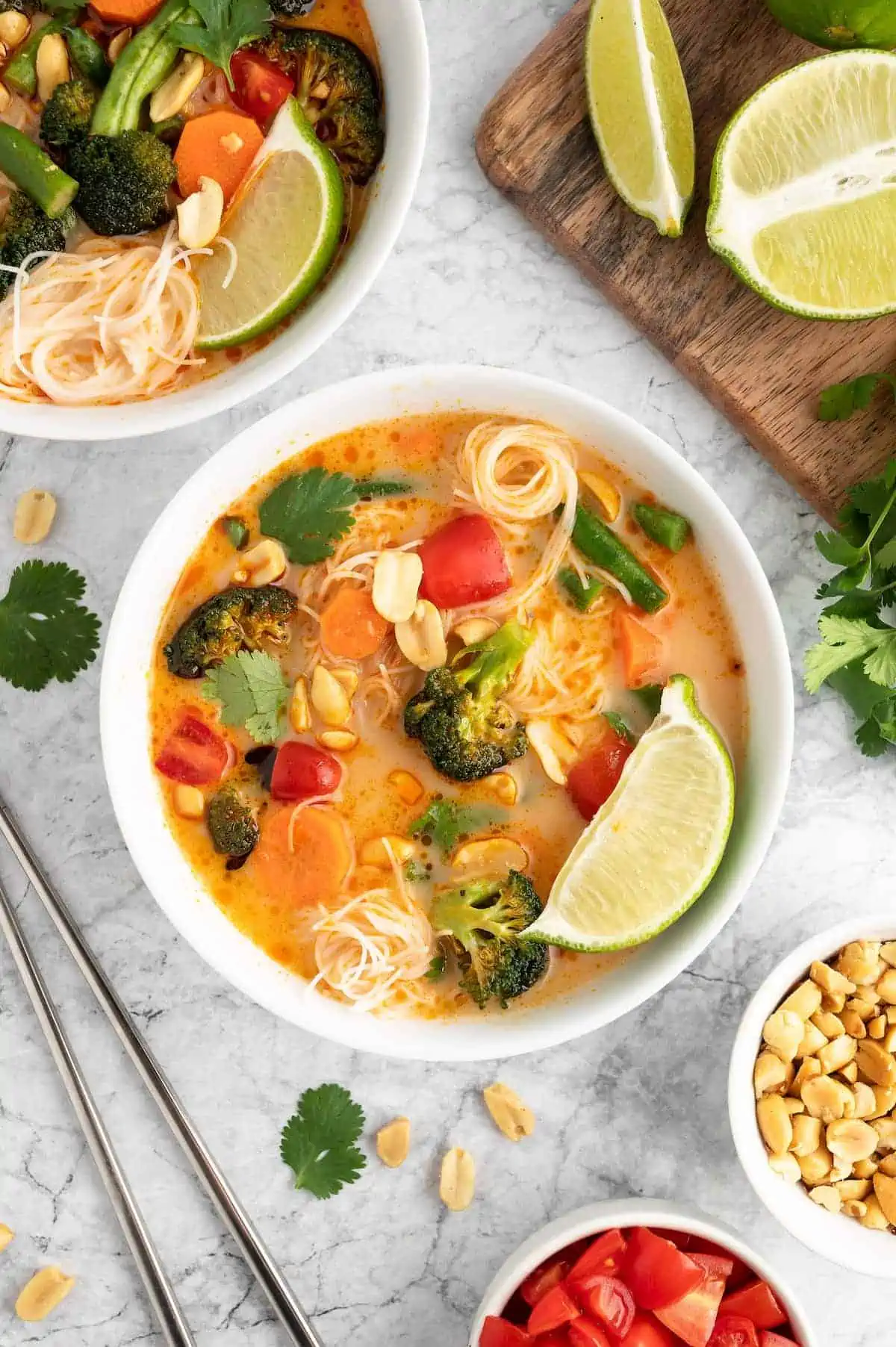 Bowls of Thai red curry noodle soup with lime and creamy coconut broth.