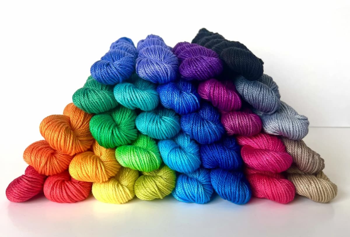 A rainbow pyramid of That's My Color vegan yarn skeins.