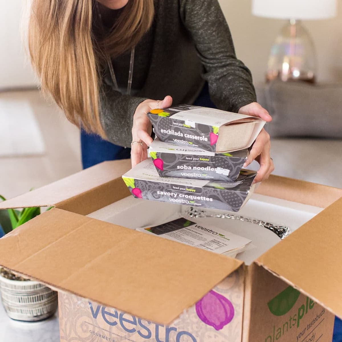 A woman unboxing a Veestro meal meal kit delivery.