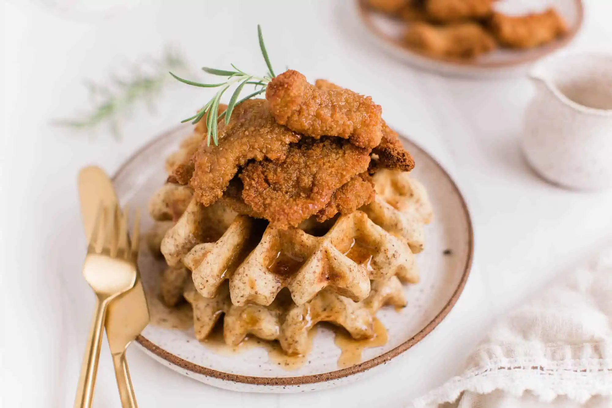 Vegan waffles stacked on a plate, topped with crispy vegan chicken strips.