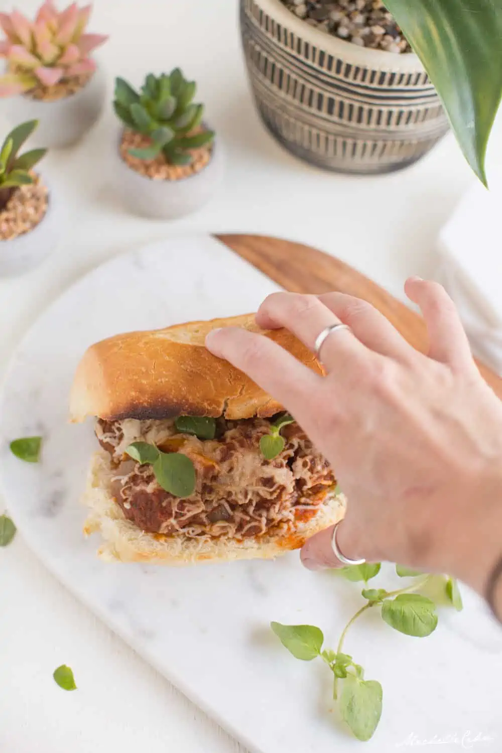 A hand reaching for a vegan meatball sub.