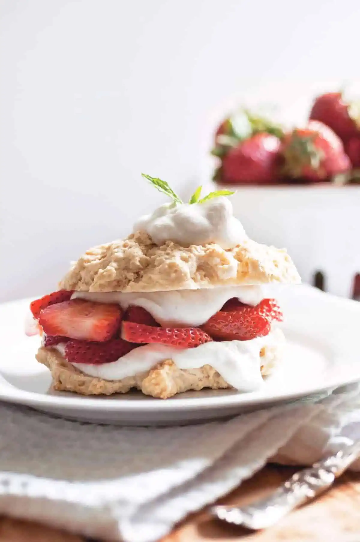 Vegan strawberry shortcake on a serving plate topped with whipped coconut cream and juicy berries.