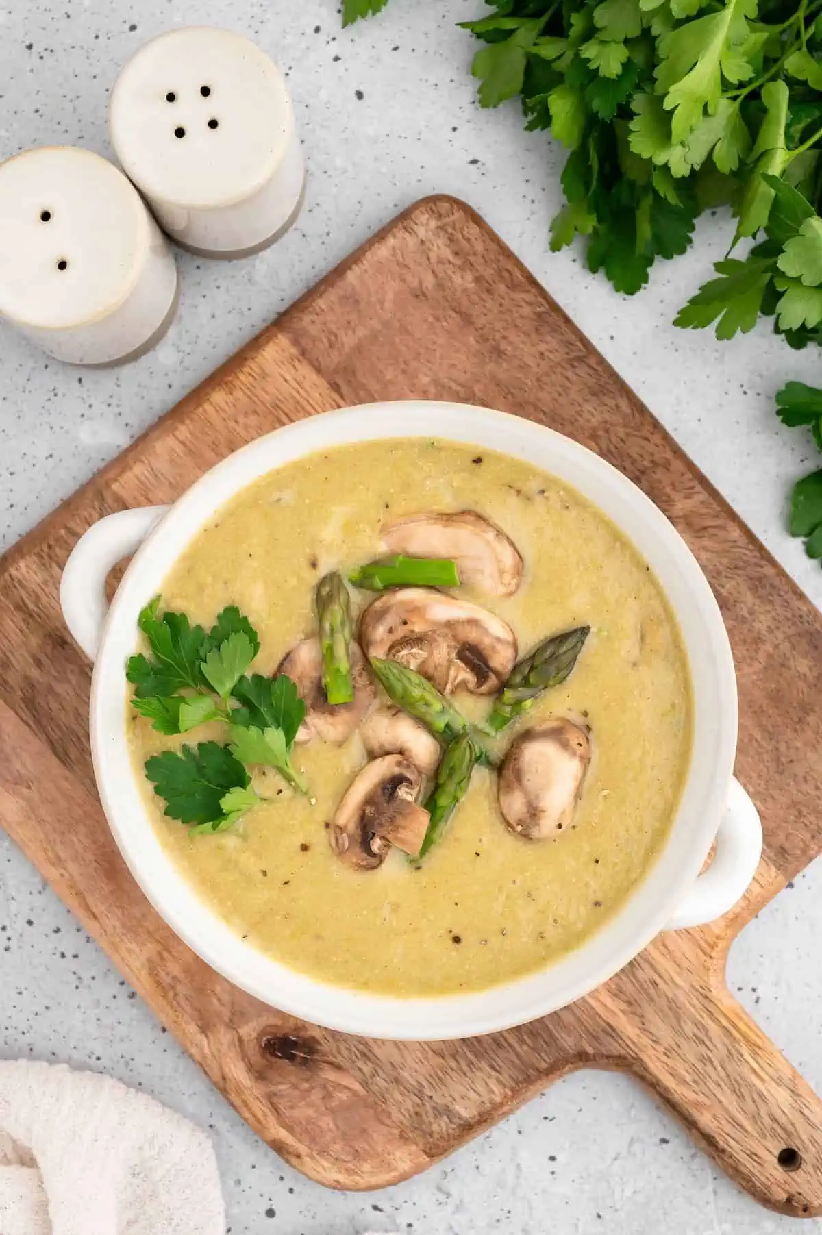 Vegan asparagus and mushroom soup in a rustic bowl on a wooden surface.