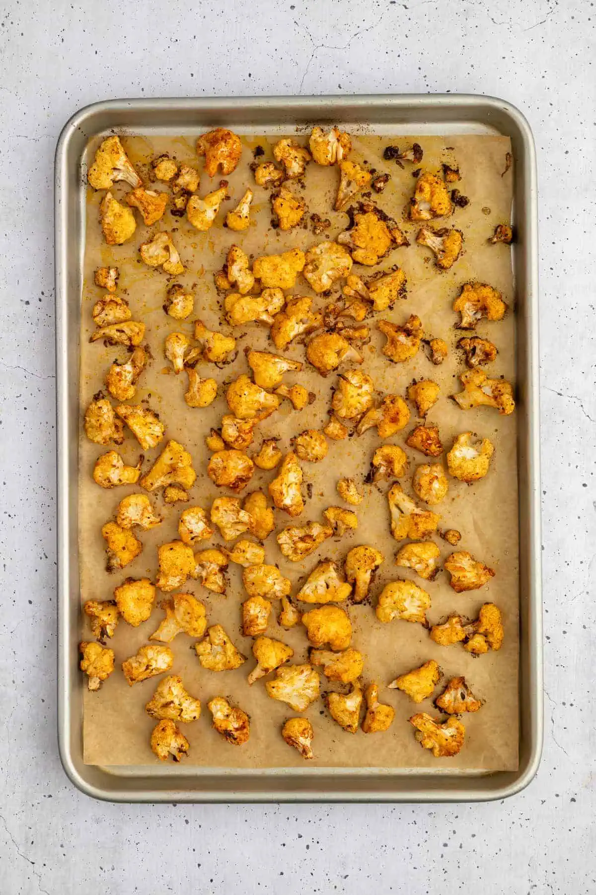 Golden-brown roasted cauliflower florets on a baking sheet, crisped to perfection.