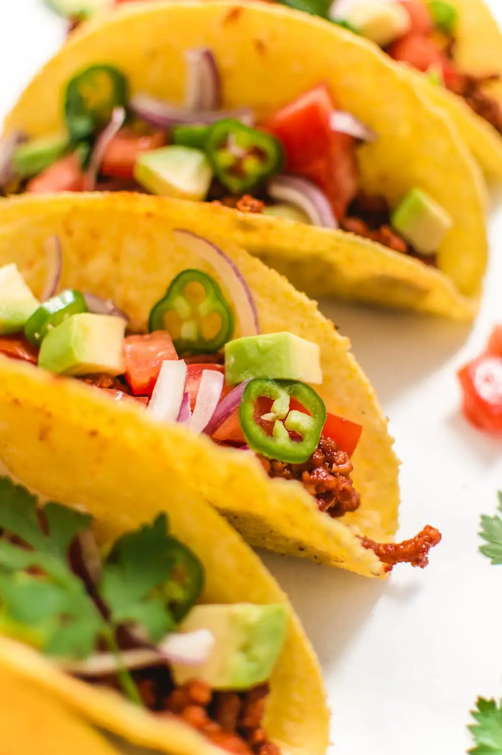 Vegan tacos close up showing many chopped vegetables in a hard corn taco shell.