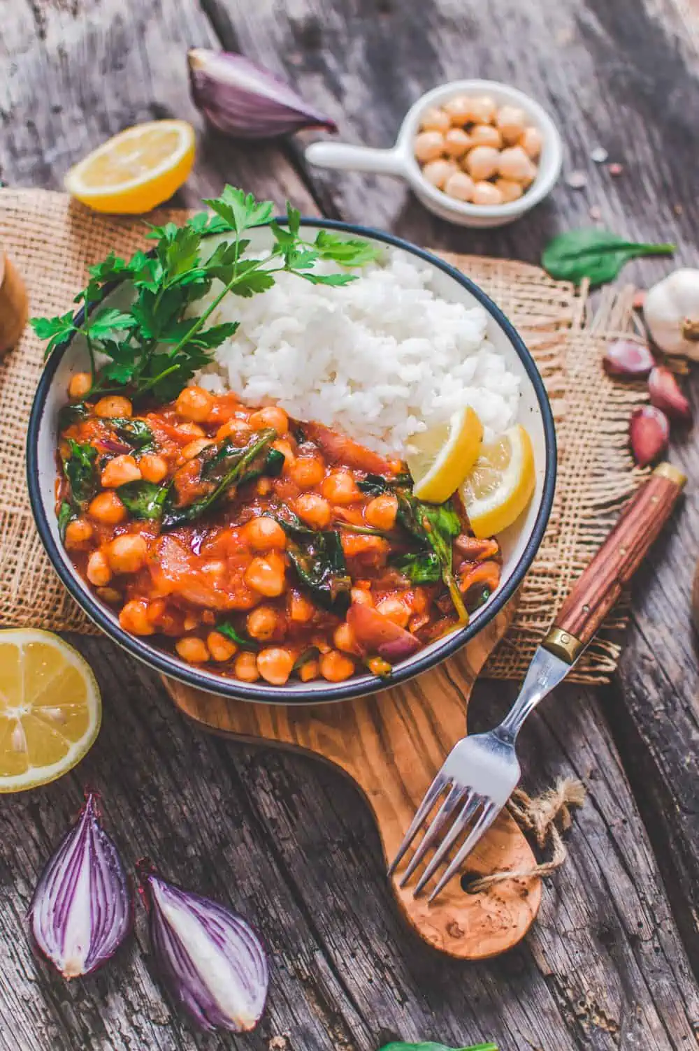 Vegan chickpea stew served in a bowl with rice and topped with parsley.