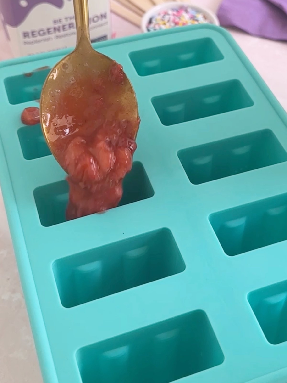 Spooning the strawberry mixture into the bottom of the popsicle molds.