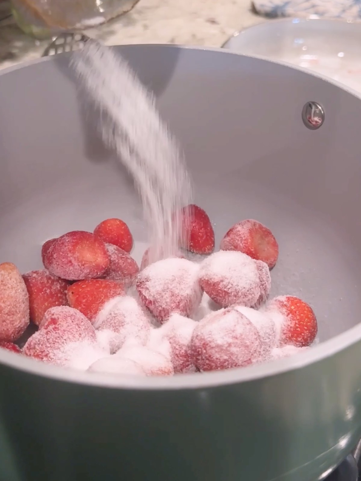 Pouring sugar and strawberries into the pot.