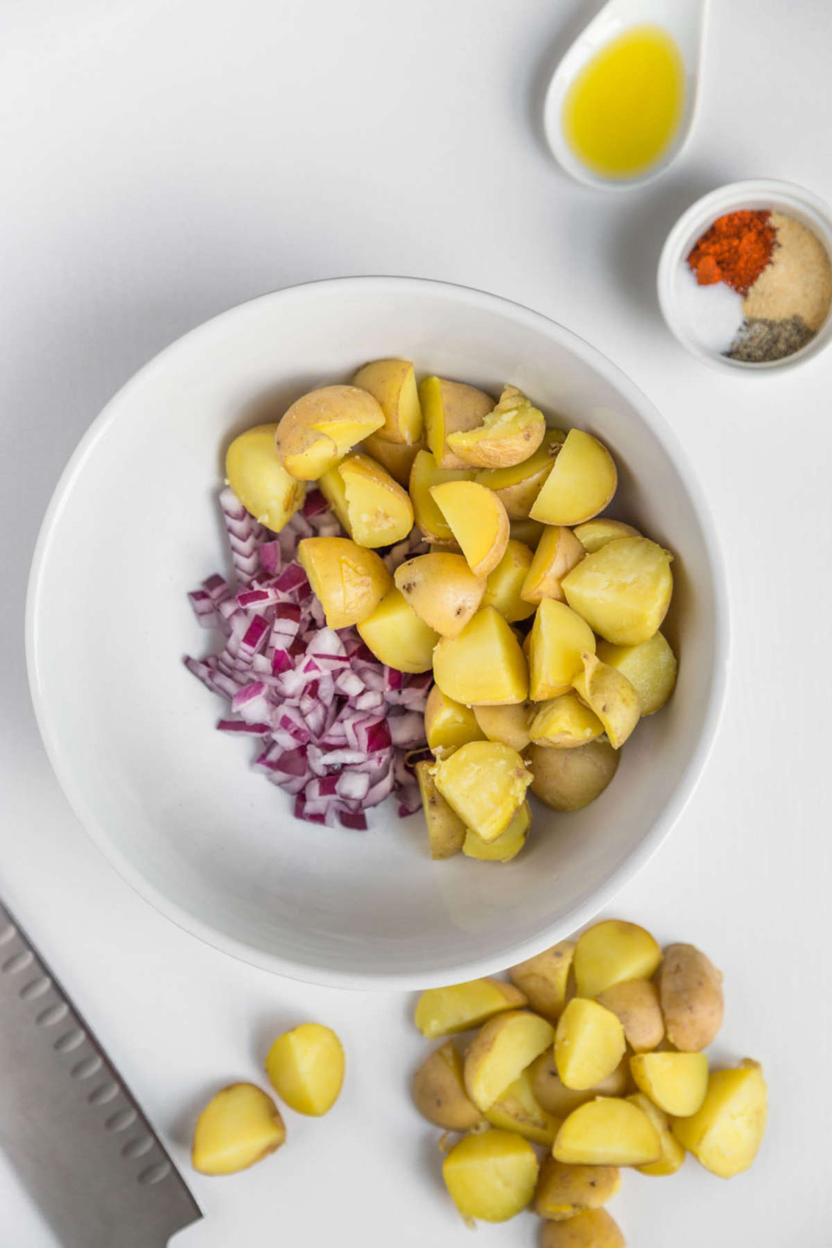 Chopped baby potatoes and red onion in a mixing bowl, prepped for seasoning and air frying.