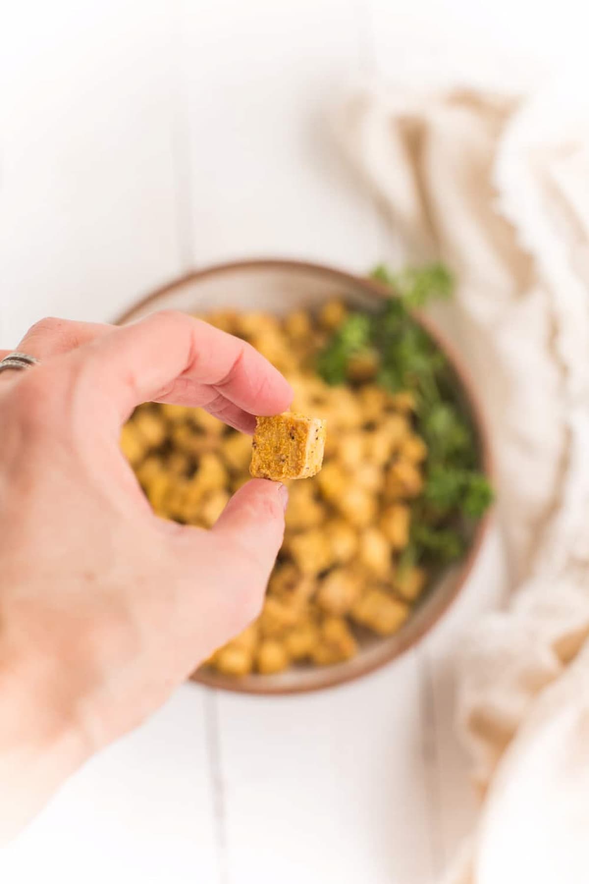 A hand holding an air-fried tofu nugget.
