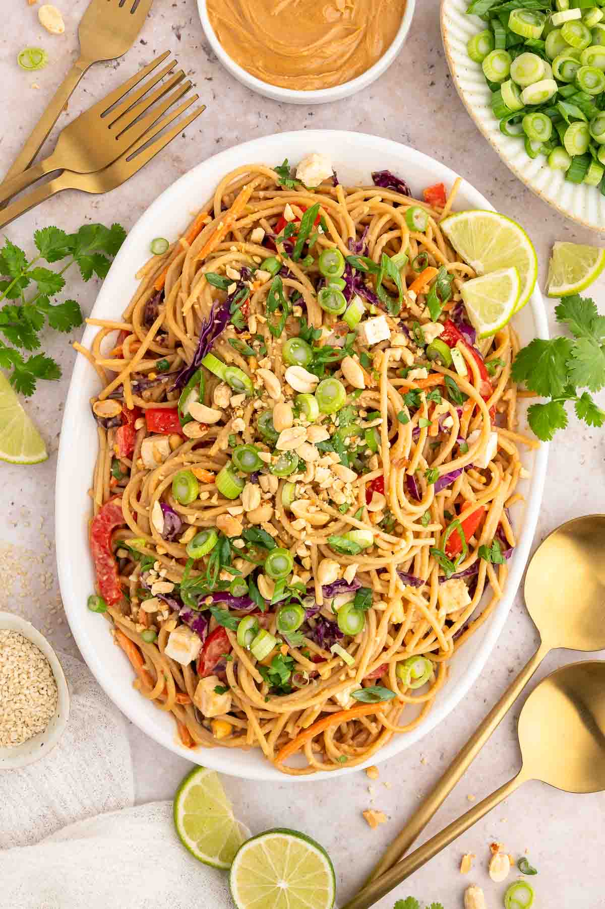 A large serving platter of this Asian cold noodle salad topped with roasted peanuts, sliced green onions, and lime wedges.