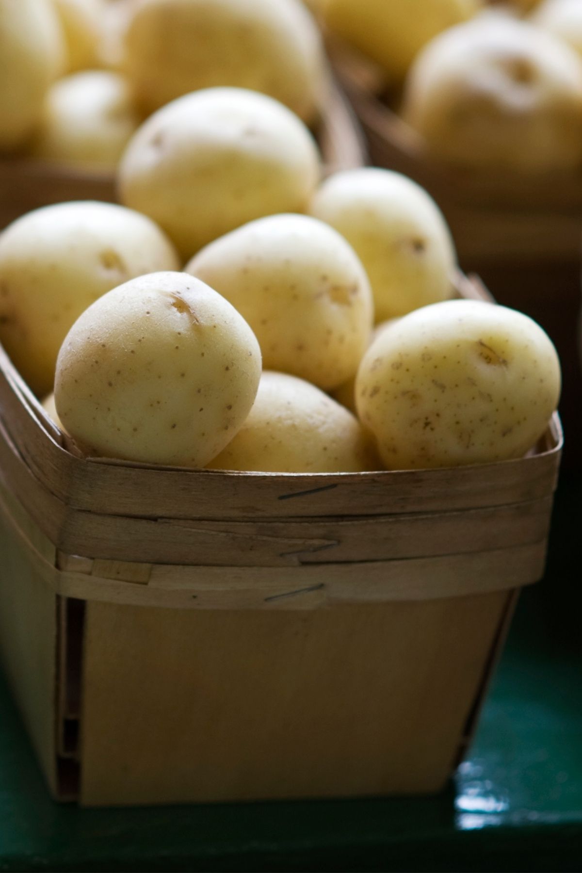 Fresh yellow potatoes in a wooden basket, perfect for vegan recipes and healthy meal ideas.