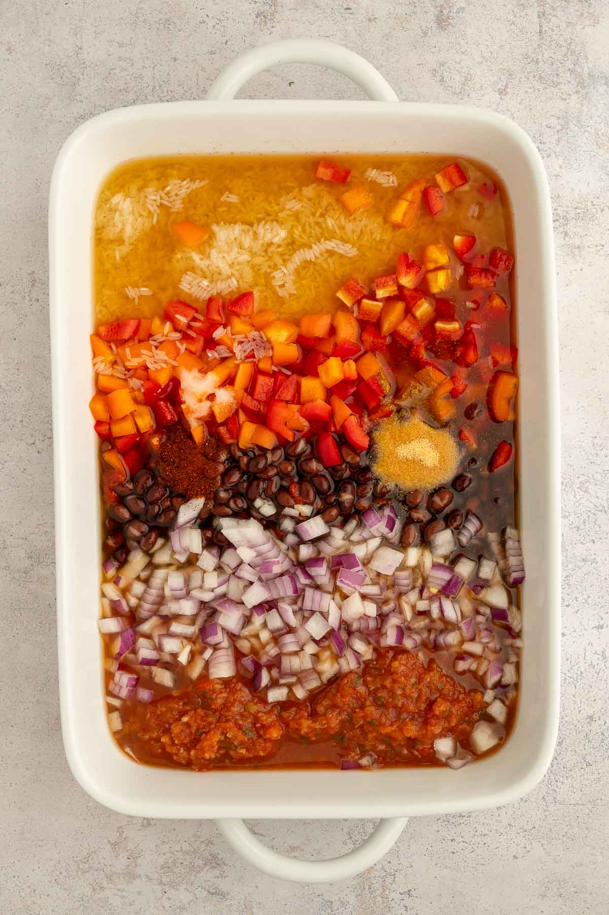 All of the ingredients for this bean and rice casserole recipe add to a large casserole dish before mixing it all together.