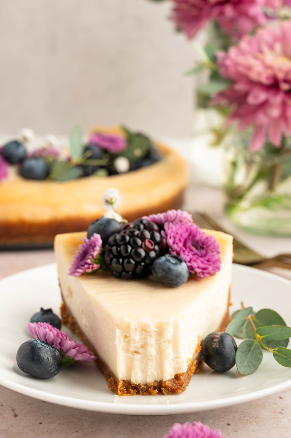 A slice of vegan cheesecake on a plate with a bite removed from it.