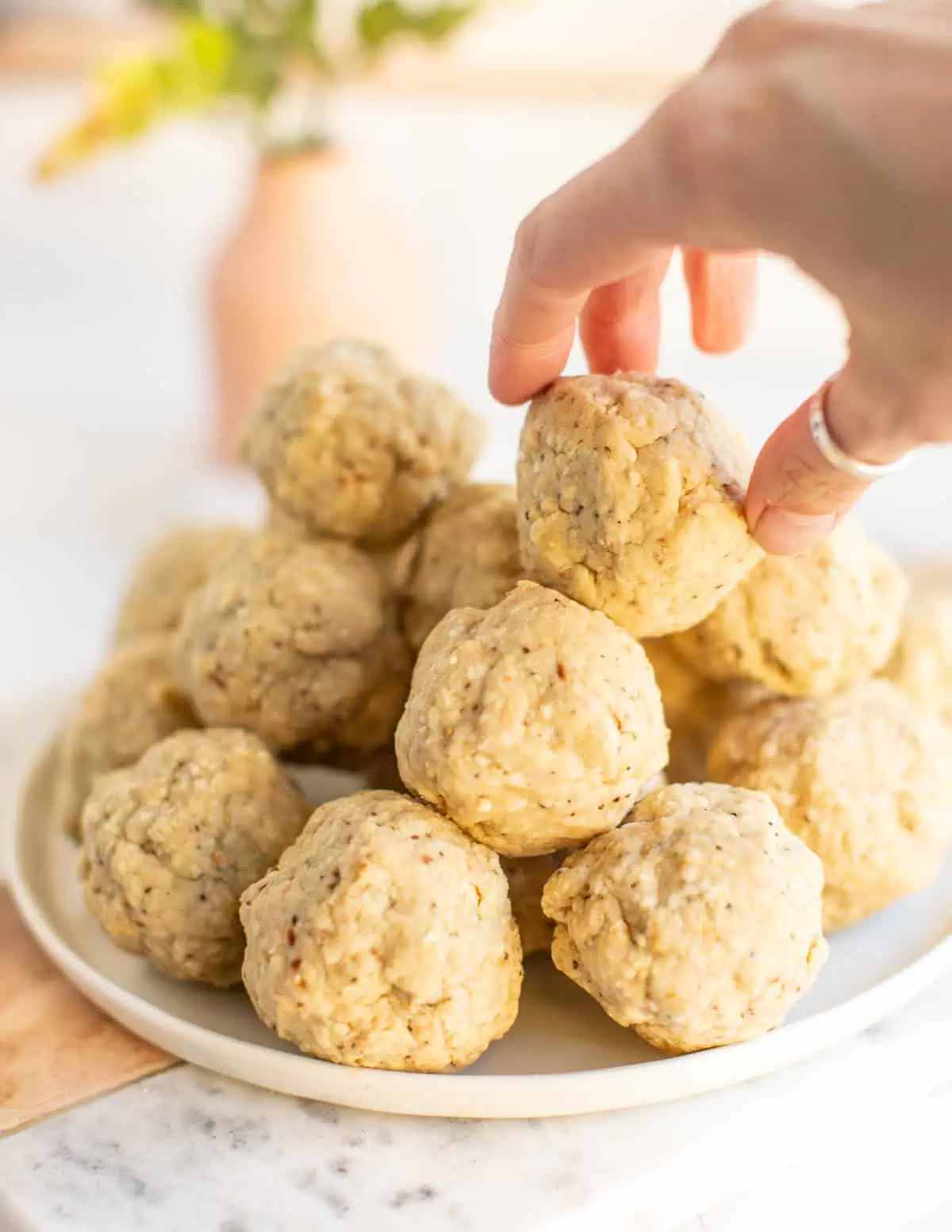 Picking up one of the vegan matzo balls stacked on a plate before adding them to the soup.