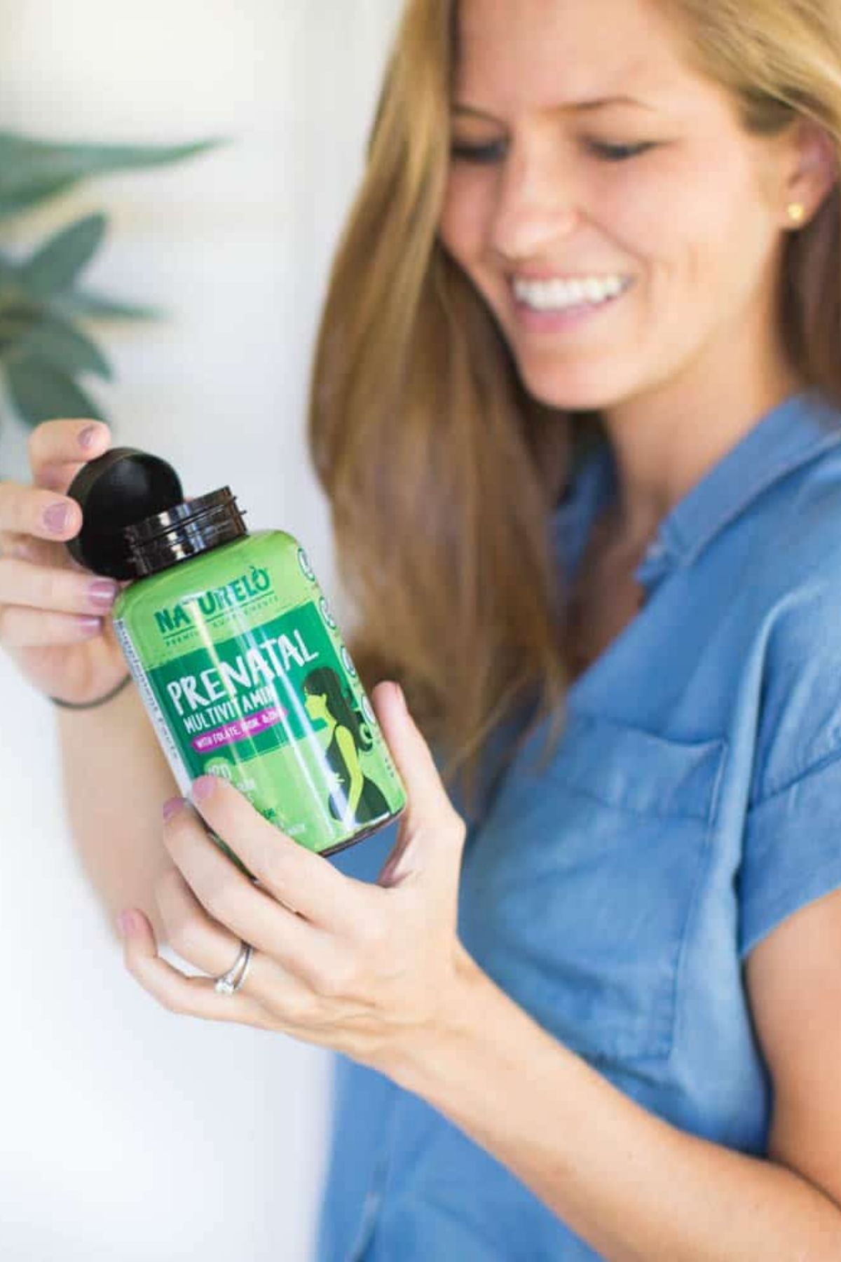 A woman holding a bottle of vegan multivitamins.